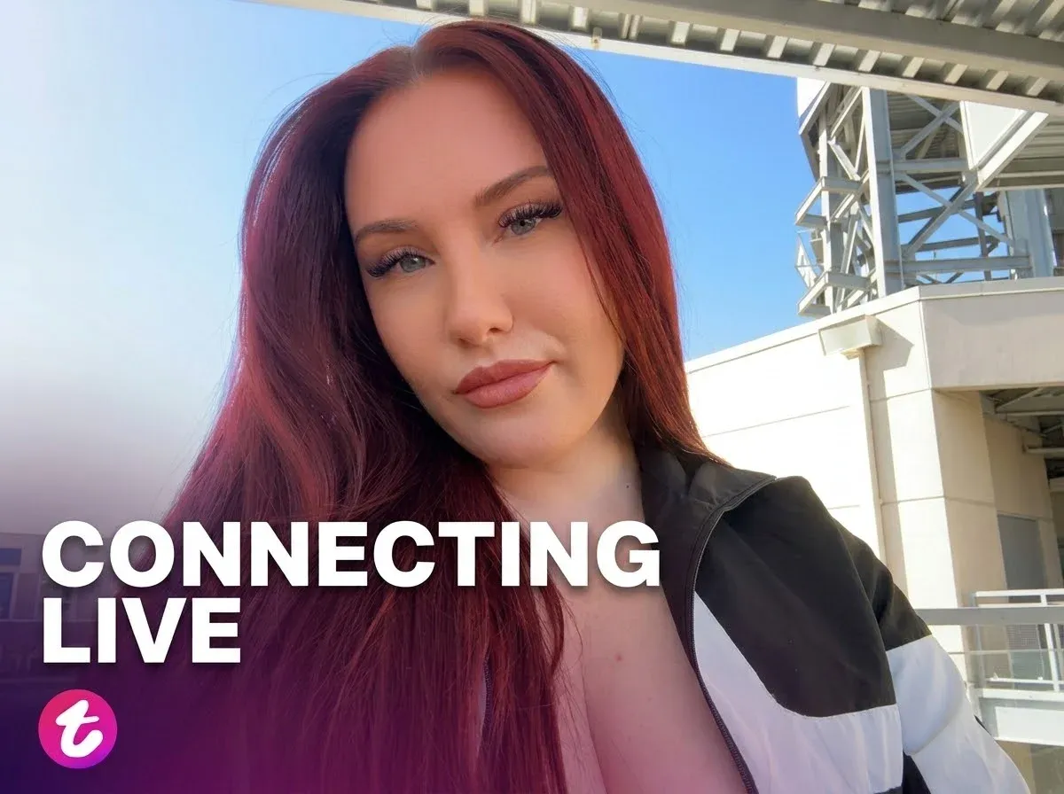 Ruby Red taking a selfie outdoors under a blue sky